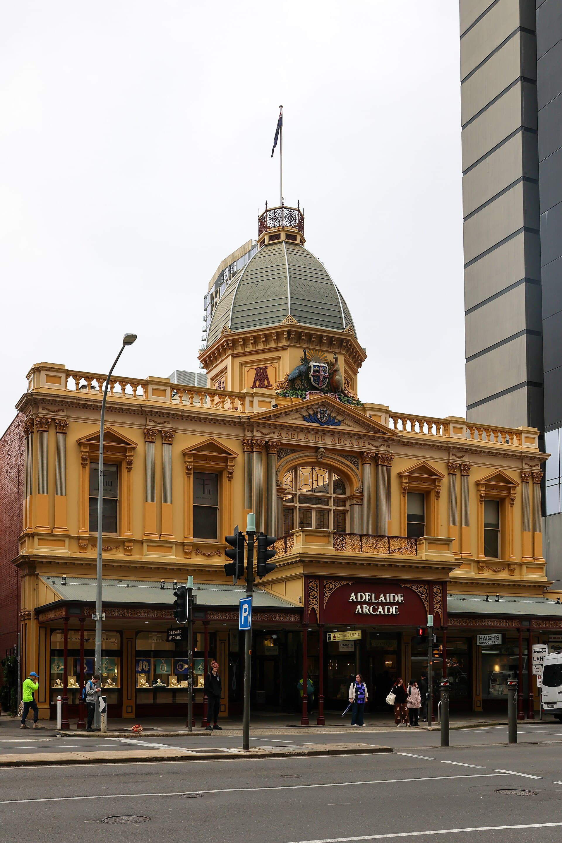 The glass-roofed interior of Adelaide Arcade, with heritage shopfronts along the tiled walk.
