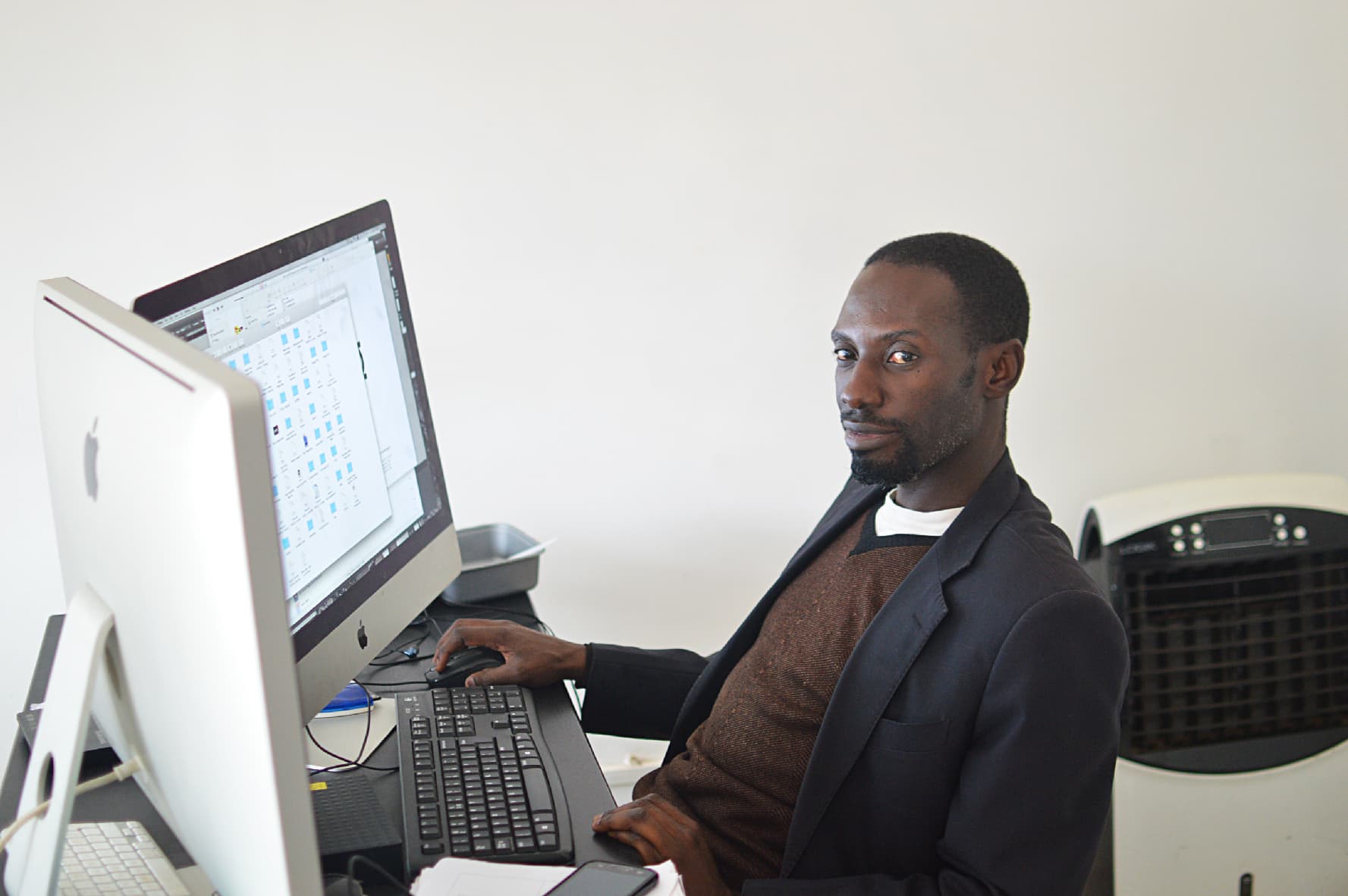 A graphic designer at a workstation with a large monitor and drawing tablet.