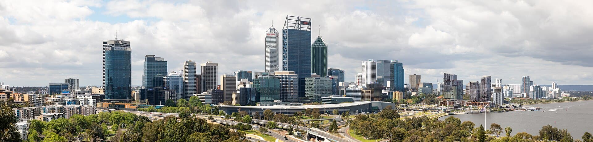 Perth skyline across the Swan River, with office towers reflected in late-afternoon light.
