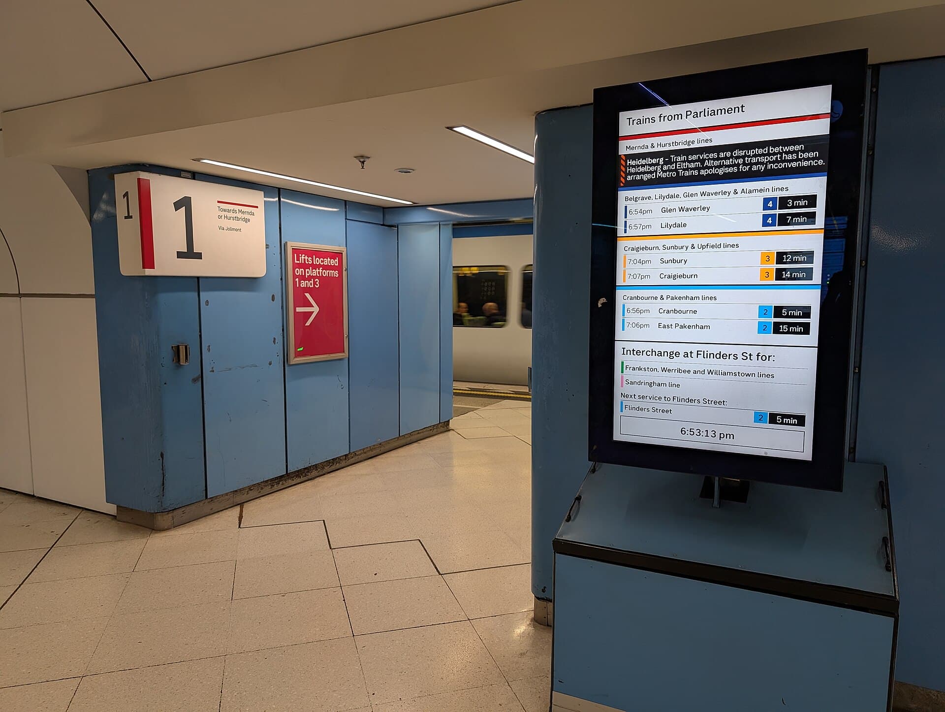Wayfinding signs and a departure screen above a platform at Parliament railway station in Melbourne.
